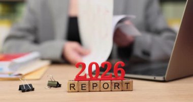 2026 raporunun belgelerini özenle inceleyen bir kişi, kağıtlar ve dizüstü bilgisayarla dolu sıcak bir masada oturuyor. Atmosfer odaklanmış ve sakin. Derin konsantrasyon için mükemmel..