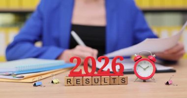 Canlı bir ofis alanında, bir kişi 2026 için anahtar sonuçlar ve stratejilerle dolu belgeleri dikkatle gözden geçirir. Odaklanmış ve kararlı bir şekilde gelecekteki zorluklara ve fırsatlara hazırlanıyorlar..