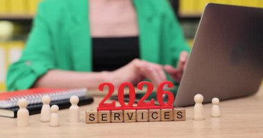 Canlı bir ofiste, bir kişi 2026 yılı için organizasyon araçları ve dekoratif unsurlarla çevrili bir tören planlıyor. Atmosfer yenilik ve verimliliği teşvik eder..