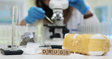 Mavi eldivenli kadın madde ve ölçek analizi için mikroskop kullanıyor. Modern adli tıp laboratuarında ilaçların bilimsel incelemesi