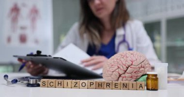 Bayan doktor, şizofreni ve beyin modelleri ile ilgili belgeleri panoda inceliyor. Zihinsel sağlık durumunun teşhisi ve çalışması ağır çekimde