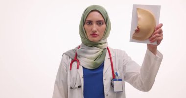 Başörtülü doktor meme modelini tutuyor ve kanserin sembolü olarak pembe kurdele gösteriyor. Müslüman hekim meme kanseri hakkında farkındalık yaratıyor. Yavaş çekim
