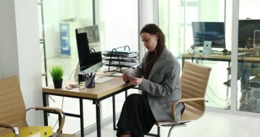 Genç bir kadın, ofis masasındaki paraları dikkatlice düzenleyen banknotları sayıyor. Eylem, para yönetimine odaklanmayı yansıtan banknotları dizen elleri gösteriyor