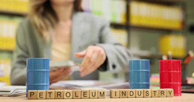 Tahta küpler, enerji sektörünü vurgulayan Petrol Endüstrisi 'ni oluşturur. Küçük petrol varilleri ve para sayan kadın, ticaret faaliyetlerini simgeliyor.