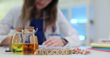 Tahta bloklar Tifo 'nun renkli sıvıyla şişelerin yanına konduğunu söyler. Işık odaya giriyor kapsüller ve test tüpleriyle tıbbi atmosfer yaratıyor.