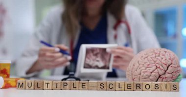 Doktor ultrason taramasını gözden geçirir ve bloklarda çoklu skleroz ve masadaki beyin modeline yakın şeyler yazar. Araştırma nörolojik durumla ilgili