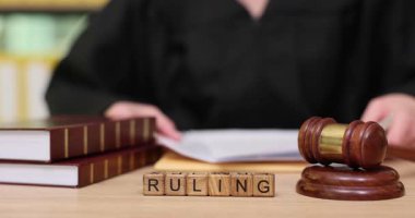 Bir yargıç, yasal kitaplar ve tokmakla çevrili bir mahkeme salonunda önemli bir dava üzerinde tartışıyor. Önemli kararlar adaleti ve toplumun refahını şekillendirir..