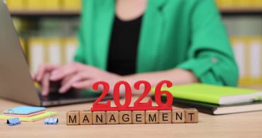 Bir kişi 2026 yılında yönetime odaklanırken geleceğe hazırlanır. Profesyonel amaçlara ulaşmak için etrafları defterler ve ofis malzemeleriyle çevrili bir dizüstü bilgisayarda çalışıyorlar..