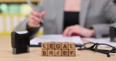 Sessiz bir ofis ortamında, bir profesyonel gayretli bir şekilde yasal bir özet hazırlıyor. Temel detayları belgelemek için pul ve gözlük gibi araçlarla doğruluğu vurguluyorlar..