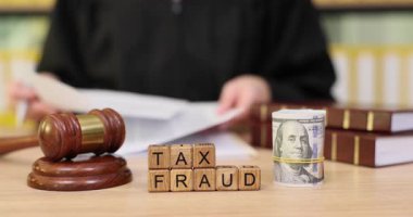 Hukuk kitaplarıyla dolu bir mahkeme salonunda, yargıç vergi kaçakçılığı kanıtlarını incelerken kağıtları gözden geçirir. Görüşmede hukuki süreçte dürüstlüğün korunması üzerinde duruluyor.