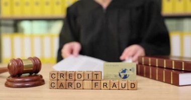 Hukuk bürosundaki kredi kartı dolandırıcılığıyla ilgili belgeleri inceleyen yasal kıyafetli bir kişi. Detaylara odaklanarak, bu yükselen sorunla mücadele etmek için çözümler arıyorlar..