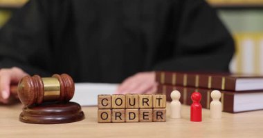 Yoğun bir mahkeme salonunda, yargıç bir davanın sonucunu belirtmek için tokmağı sıkıca vurur. Mahkeme kararı açıklanırken küçük rakamlar beklemede, adaletin yerini bulduğunu vurguluyorlar.