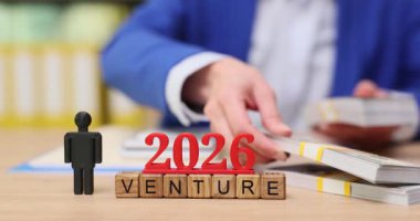 Aydınlık bir günde, bir kişi 2026 için gelecek girişimleri planlamaya olan bağlılığını gösteren finansal belgeleri dikkatlice düzenler. Takım çalışmasına ve vizyona odaklanılır..