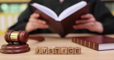 Kitaplarla dolu sakin bir ortamda, yargıç adaleti düşünür. Gözler odaklanmış, eller sayfaları çevirirken, bir tokmak ve harf blokları anlamlı bir bağlantı oluşturur.