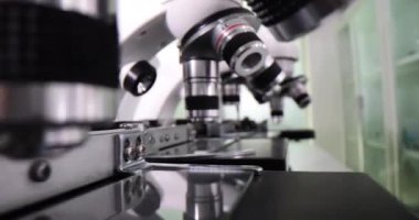 Bilimsel laboratuvarda düzenlenmiş cam slaytlarla hazırlanmış mikroskoplar. Tıp merkezindeki numuneleri araştırmak için kullanılan modern optik ekipmanlar