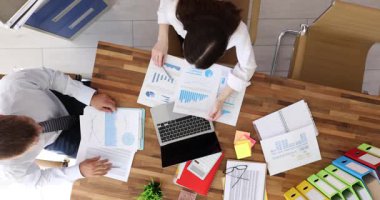 Meslektaşlar, ofisteki diyagramlar ve yumruklar hakkındaki finansal verileri gözden geçirirler. İş uzmanları iş alanındaki satış raporlarını yavaş çekimde analiz ederler