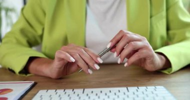 Genç bayan ofis çalışanı masa başında sürekli olarak kalemi açıp kapatıyor. Endişeli iş kadını gergin bir şekilde klavyenin yanında önemli bir toplantı bekliyor.