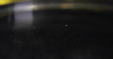 Altın damla karanlık havuza düşerken dairesel dalga dışarı doğru yayılıyor. Sıvı kısa taçlar ve parlak yüzeye geri yerleşen halka formları