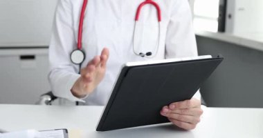 Doktor kadın brifing sırasında tedavi planını sunan bir tablet tutuyor. Tıbbi uzman hasta için online oturum yürütüyor.
