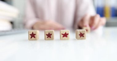 Kadın eli masaya dört yıldız bloğu yerleştiriyor ve gülümsüyor. Beşinci küpü elle yerleştirir ve mükemmel servis skorunu gösteren derecelendirme satırını tamamlar