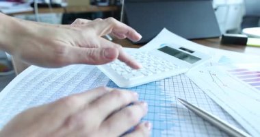 Muhasebeci hesap çizelgesinde hesap makinesi tuşlarına basar. İşçi toplamları doğruladı ve aylık rapor hazırlayan rakamları girdi