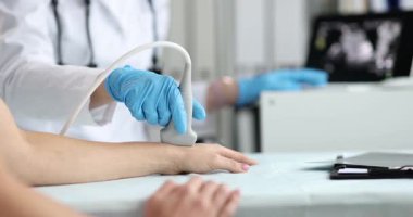 Ultrason cihazı tarama için bileğe dokunurken hasta kolu masada dinleniyor. Klinisyen taramaları tendonlar ve damarlar kayıt bulguları için dönüştürücü hareket