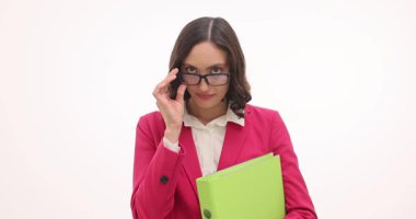 Güzel iş kadını, gözlüğü beyaz arka planda yüzük klasörü olarak tutuyor. Utangaç kadın şirket çalışanı ofis çalışma alanına bakıyor.