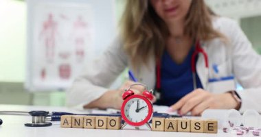 Ahşap bloklar Andropause kelimesini kırmızı alarmın yanında kadın doktor masasında çalışırken hecelerler. Kadın uzman, erkek hormon sorunu hakkında notlar yazıyor.