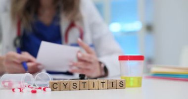 Tahta bloklar, masada sistit, idrar örneği kutusu ve kapsüllerin yanında okunuyor. Kadın ürolog idrar sorunuyla ilgili sonuç notu okudu