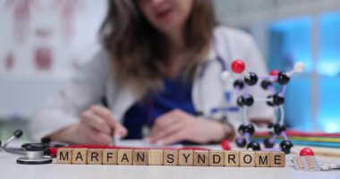 Marfan sendromuna ilaç ve steteskop ile tahta bloklar yaz. Genetik bozukluk insanların olağandışı uzun uzuvlara sahip olmasına neden olur.