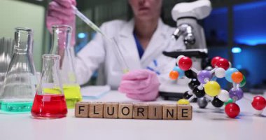 Tahta bloklara renk sıvıları ve laboratuardaki moleküler yapı modeli sayesinde flüorin. Kadın bilim adamı tıp merkezinde sıvılarla deneyler yapıyor.