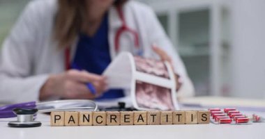 Doktor, hastanın pankreasının ultrason görüntülerini inceliyor. Tahta küpler düzgün yerleştirilmiş. Pankreas kelimesi şüpheli teşhisi simgeliyor.