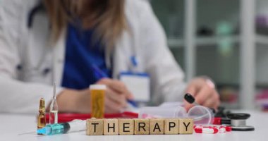 Ahşap blok sırası klinik masa yüzeyinde şırınga ve ampullerle kelime terapisi anlamına gelir. Kadın doktor tıbbi tabloları doldurup tedavi araçları hazırlıyor