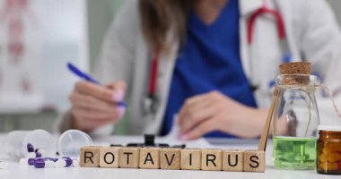 Ahşap bloklar, Rotavirüs kelimesinin yeşil çözeltiye yakın olanını şişede hecelerler. Bulaşıcı hastalıklar uzmanı randevuda yayılan rotavirüsü inceleyen notlar yazıyor.