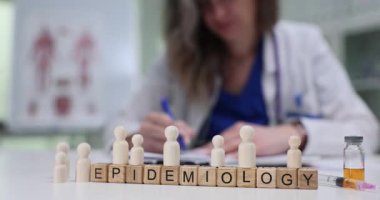 Tahta bloklar Epidemiyoloji kelimesinin harfleri ve ahşap figürler. Halk sağlığı doktoru epidemiyoloji modunu açıklayan enfeksiyon rotalarını haritalandırdı