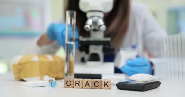 Tahta bloklar laboratuvar masasında ölçekli cihazların yanında kelime çatlağı oluşturuyor. Laboratuvar bilim adamı, iş yerinde toksikoloji raporu hazırlarken crack örneğini test etti