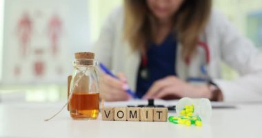 Klinik masadaki tahta küpler kusmuk kelimesini hecelerken doktor şişe ve tabletlerin yanına plan yazıyor. Kadın mide bulantısı ve susuzluk tehlikesi üzerinde çalışıyor.