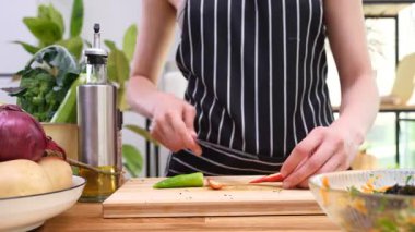 Ev hanımı acı biberi temizliyor ve tahta kesme tahtasıyla küçük parçalara ayırıyor. Kadın masadaki baharatlı biberden tohum topluyor. Zaman aşımı