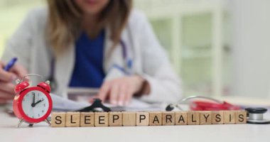 Tahta bloklar ve çalışan doktora karşı vi9ntage çalar saat üzerinde Uyku Felci deyimi. Doktor, hastanedeki hasta kayıtlarını okuyor.