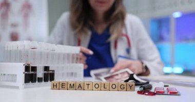 Tahta küplerle ilgili kelime hematolojisi tüplerde kan örnekleri ve hastanede ilaçlar. Kadın doktor, tıp laboratuarındaki ultrason taramalarını kontrol ediyor.