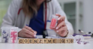 Koenzim Q10 'u ahşap bloklara dağılmış renkli kapsüllerle doktor masasına yaz. Doğal olarak oluşan Ubiquinone biyokimyasal kofaktör ve antioksidan