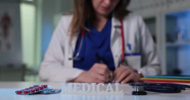 Tıbbi ilaçlar ve steteskop yanında kadın doktorların çalıştığı yerde. Doktor hastaya reçete yazıyor. Sağlık hizmetleri