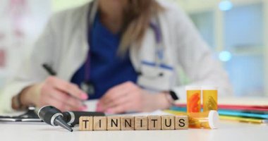 Otoskop yakınındaki tahta bloklarda Tinnitus ve doktor işyerindeki ilaç kapları. Kadın sıhhiyeci hastanede kulak çınlaması tedavisi uyguluyor