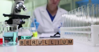 Beryllium 'u cam küpler arasında mikroskopla bilim adamlarının masasına yaz. Kadın kimyager laboratuardaki test sonuçları hakkında rapor dolduruyor.