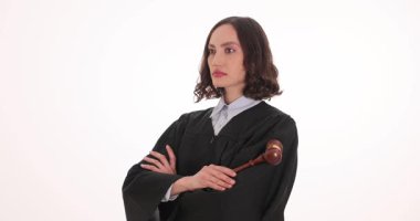 Siyah cüppeli kadın yargıç tokmağı tutarken kolları çapraz duruyor. Kadın yargıç ağır çekimde önemli bir davaya sıkı hazırlanıyor gibi görünüyor.