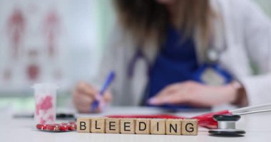 Tahta bloklar kelimenin kısaltılmışı hapların ve test tüpünün yanında kanama. Kadın doktor randevuda semptomları dikkatle incelerken kan kaybı hakkında not yazar.