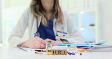 Tahta bloklar, şişenin yanında kısa vadeli rehine ve masada haplar demek. Kadın doktor, hasta için hormon terapisi dozu kayıt programı planlıyor