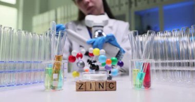 Masadaki tahta küpler renkli boruların yanında çinko kelimesini heceliyor. Kimya uzmanı yavaş çekim testi için çoklu pipeti ayarladı