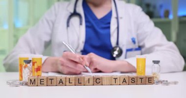 Doktor semptomları gözden geçirir ve randevuda tabletler için reçete yazar. Tabloda küçük tahta bloklar oluşturulduğunda Metalik Tat