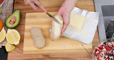 Şef, yumuşak beyaz ekmek dilimlerine kremalı tereyağı serpmek için küçük bıçak kullanır. Aşçı öğle yemeği için lezzetli sandviçler hazırlar.